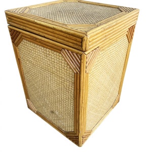 May include: A woven wicker storage box with a lid. The box is made of natural colored rattan and has a square shape.