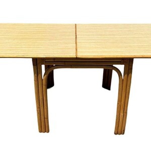 May include: A rectangular, light brown bamboo dining table with a woven top and four legs. The table is made of natural materials and has a simple, elegant design.