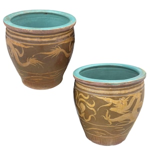 May include: Two brown ceramic planters with teal interiors and gold dragon designs. The planters have a wide opening and a slightly tapered body. The rims are accented with a pinkish-beige band.