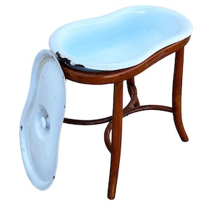 May include: A kidney-shaped white enamel basin with a matching lid, supported by a brown bentwood stand with four curved legs. The basin features visible dark wear along the rim, and the wooden frame includes curved structural supports.