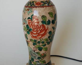 May include: A porcelain table lamp with a white base and floral design. The lamp has a gold-colored base and a floral pattern with red, green, and blue accents.