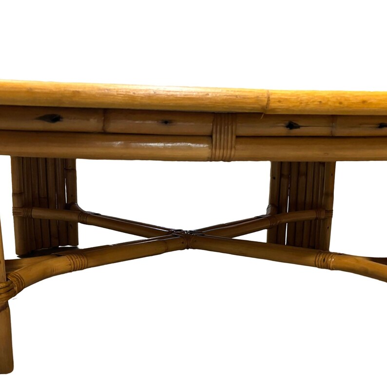 Pode incluir: Uma mesa de centro redonda de madeira com tampo de bambu tran&ccedil;ado e base em forma de cruz.