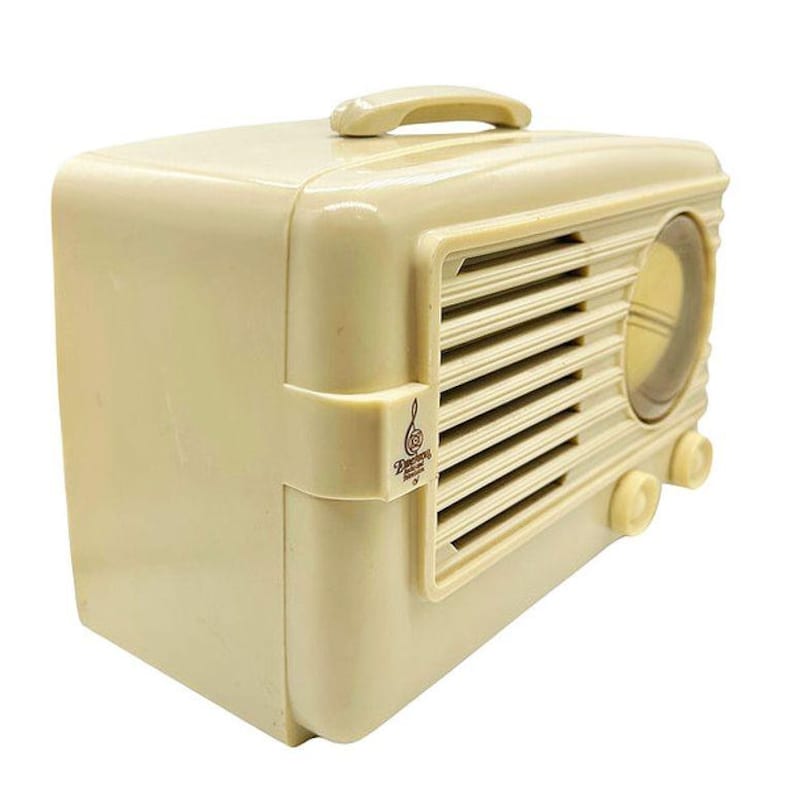 Puede incluir: Radio vintage de color crema con asa en la parte superior. La radio tiene una rejilla de altavoz, un dial de sintonizaci&oacute;n y perillas de control. La palabra "Deering" est&aacute; impresa en el lateral. La radio es de estilo retro.