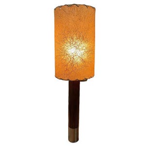May include: A mid-century modern lamp with a brown wooden base and a cylindrical, off-white lampshade with a woven texture.