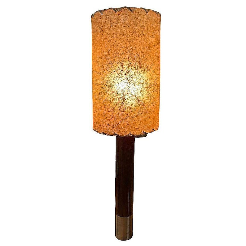 May include: A mid-century modern lamp with a brown wooden base and a cylindrical, off-white lampshade with a woven texture.