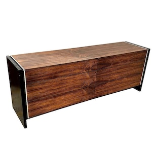 May include: A six-drawer dresser made of dark wood with black trim. The drawers have a wood grain pattern.