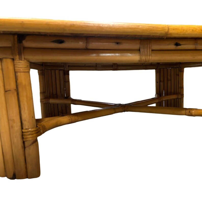 Pode incluir: Uma mesa de centro redonda de bambu natural com tampo tecido e base em forma de cruz.