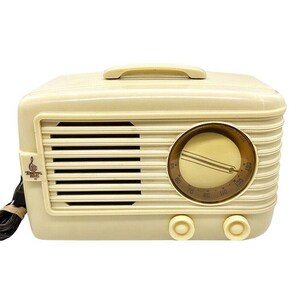 Puede incluir: Radio vintage de color crema con asa, rejilla de altavoz y dial de sintonizaci&oacute;n. La radio tiene dos perillas y un peque&ntilde;o logotipo en el lado izquierdo. El dial presenta n&uacute;meros y una aguja. Un cable de alimentaci&oacute;n negro se extiende.