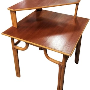 May include: A two-tiered bamboo end table with a rectangular top and a triangular top shelf. The table has a natural bamboo finish and is made of woven bamboo.