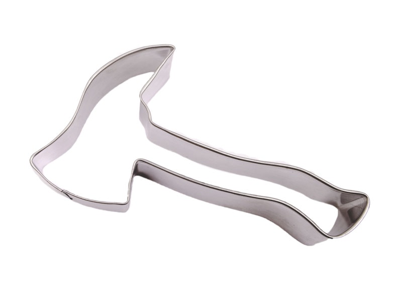 May include: A stainless steel axe-shaped cookie cutter. The cutter has a detailed outline of an axe head and handle. The metal has a shiny, reflective surface, and the design is suitable for baking.