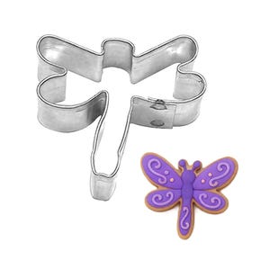 May include: A stainless steel dragonfly-shaped cookie cutter next to a decorated cookie. The cookie is purple with brown icing and decorative swirls. The cookie cutter is made of shiny, silver-colored metal.