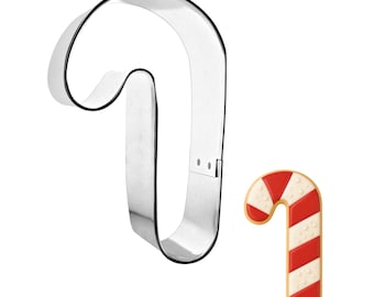 May include: A shiny, silver candy cane-shaped cookie cutter next to a decorated candy cane cookie. The cookie has red and white stripes with white dots, and a light brown border. Perfect for holiday baking.