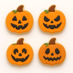 May include: Four Halloween-themed sugar cookies shaped like jack-o'-lanterns. Each cookie has an orange pumpkin with a brown stem and green leaf. The jack-o'-lantern faces are cut out with black icing. The cookies are on a white background.