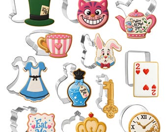 May include: A collection of metal cookie cutters paired with matching decorated cookies featuring a green top hat, a pink cat face, a teapot with text, a striped teacup, a white rabbit, a blue dress, a blue potion bottle, a key, a playing card, an Eat Me sign, a crown, and a clock.