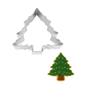 May include: A silver-colored Christmas tree-shaped cookie cutter next to a decorated Christmas tree cookie. The cookie is green with white dots and a brown base. The cutter is made of metal.