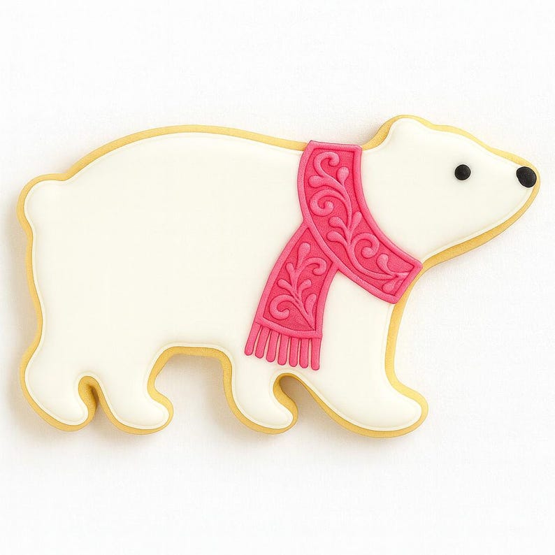May include: A polar bear cookie with white icing, a pink scarf, and black eyes. The cookie has a yellow outline and is decorated with intricate details. This festive treat is perfect for a holiday celebration.