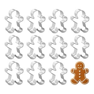 May include: A collection of twelve gingerbread man cookie cutters, eleven in silver metal and one baked gingerbread cookie. The cookie has white icing details and a smiling face.