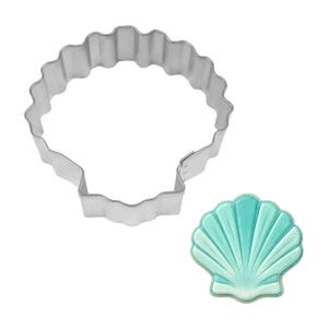 May include: A seashell-shaped cookie cutter made of shiny, silver metal. Next to it is a seashell-shaped cookie with a light blue and turquoise color scheme. The cookie has detailed lines to mimic the shell's texture.