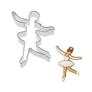 May include: A stainless steel ballerina-shaped cookie cutter next to a decorated sugar cookie in the shape of a ballerina. The cookie has a white tutu, brown hair, and a small crown.