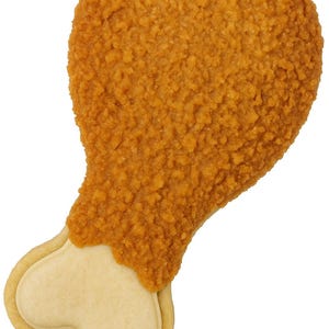 May include: A cookie shaped like a fried chicken leg. The top portion is covered in a textured, golden-brown coating, while the bottom is a light tan color, resembling the bone. The cookie is set against a plain white background.