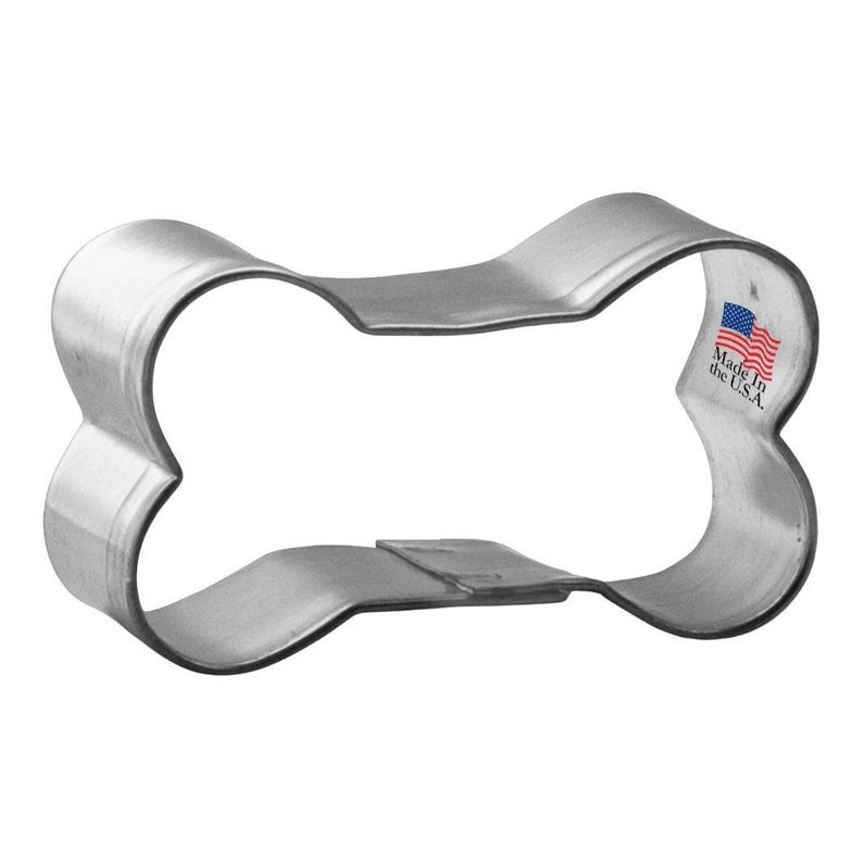 May include: A silver metal dog bone cookie cutter. The cutter is made in the USA.