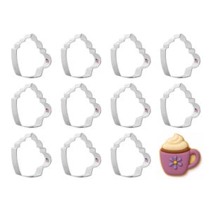 May include: A collection of eleven silver-colored metal cookie cutters in the shape of a coffee cup with whipped cream, plus one decorated cookie. The cookie cutters have a small American flag detail. The decorated cookie is purple with a flower.