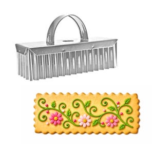 May include: A rectangular stainless steel cookie cutter with a fluted edge and a top handle, positioned above a rectangular cookie with scalloped edges, decorated with green icing vines, leaves, and pink and white flower-shaped sugar candies.