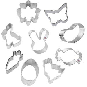 May include: A set of nine metal cookie cutters in various shapes, including a butterfly, bunny, carrot, egg, flower, and chick. The cutters are silver and have a shiny finish.