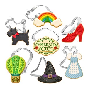 May include: A set of seven metal cookie cutters paired with matching decorated cookies. Shapes include a black dog with a red bow, a rainbow with clouds, a red high-heeled shoe, a green hot air balloon, a black witch hat, a blue gingham dress, and a plaque reading Emerald City.