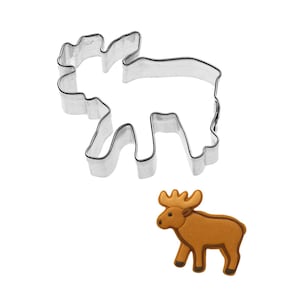 May include: A stainless steel moose-shaped cookie cutter next to a brown moose-shaped cookie. The cookie cutter is a detailed outline of a moose. The cookie is brown with darker brown details.