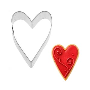 May include: A heart-shaped cookie cutter made of shiny metal next to a decorated heart-shaped cookie. The cookie has a red icing with a decorative swirl design and small dots. The cookie has a golden-brown edge.
