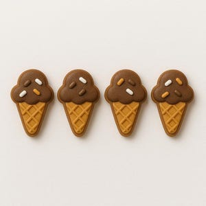 May include: Four ice cream cone-shaped cookies with chocolate frosting and sprinkles. The cones are a light brown color, and the frosting is dark brown. The sprinkles are white and orange. The cookies are arranged in a row on a white background.