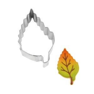 May include: A leaf-shaped cookie cutter made of shiny, silver metal next to a decorated leaf-shaped cookie. The cookie has a gradient of colors, including yellow, orange, and green, with brown veins.