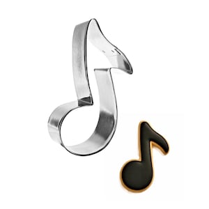 May include: A stainless steel musical note cookie cutter next to a decorated cookie in the shape of a musical note. The cookie is black with a tan border. The cookie cutter is a shiny silver color.
