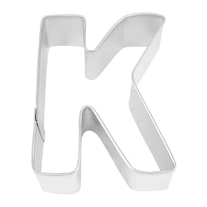 May include: A silver metal cookie cutter shaped like the letter K.