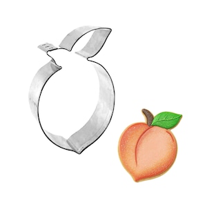 May include: A stainless steel peach-shaped cookie cutter next to a decorated peach cookie. The cookie is orange and pink with a green leaf and brown stem. The cookie cutter is a simple outline of a peach.