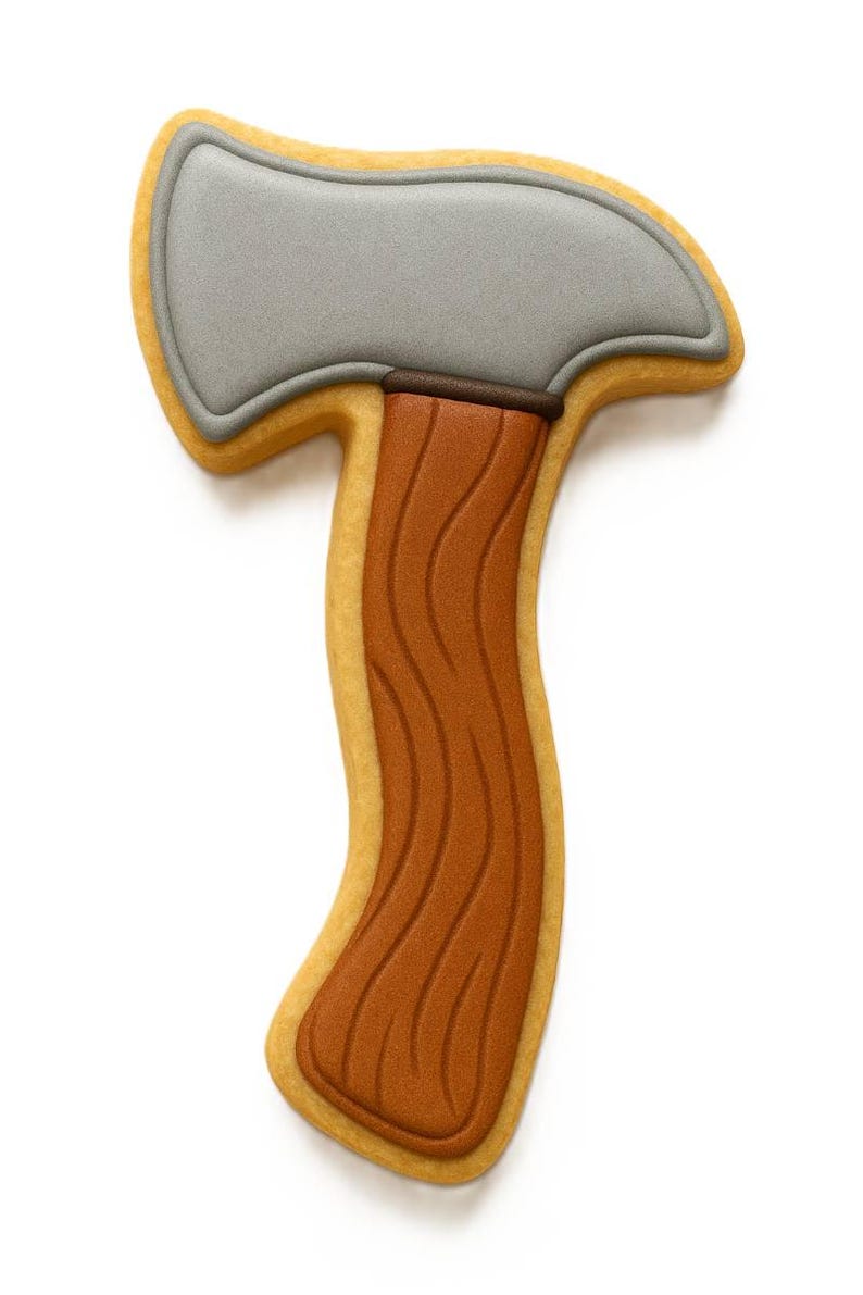 May include: An axe-shaped biscuit. The axe head is grey, the handle is brown with a wood grain effect, and the biscuit is outlined in yellow. The biscuit is set against a white backdrop.