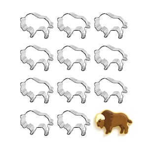 May include: A collection of eleven silver-colored metal bison-shaped cookie cutters and one decorated bison cookie. The cookie is brown with a white and tan head and a yellow outline.
