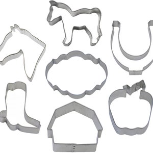 Puede incluir: Conjunto de siete cortadores de galletas de metal en forma de cabeza de caballo, caballo, herradura, granero, bota, manzana y pancarta. Los cortadores son de color plateado y tienen un acabado liso y pulido.
