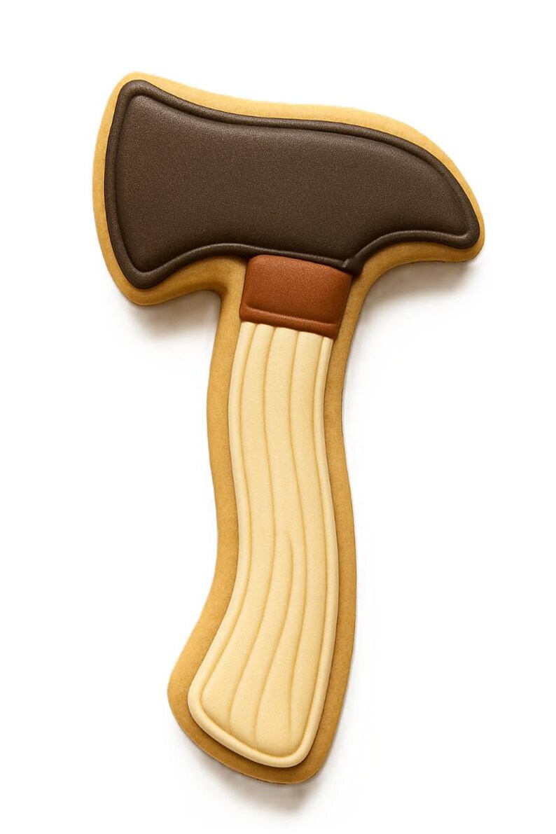 May include: An axe-shaped biscuit. The axe head is dark brown, the handle is light brown with vertical lines, and the outline is a light tan colour. The biscuit is set against a white background.