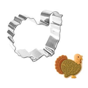 Puede incluir: Un cortador de galletas plateado brillante en forma de pavo con borde ondulado. Junto a &eacute;l, una galleta decorativa con forma de pavo con un dise&ntilde;o marr&oacute;n, naranja y amarillo. Perfecto para hornear en oto&ntilde;o o en Acci&oacute;n de Gracias.