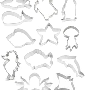 May include: A set of 12 metal cookie cutters shaped like various sea creatures, including a shark, turtle, penguin, whale, seashell, starfish, jellyfish, seahorse, fish, dolphin, stingray, and crab.