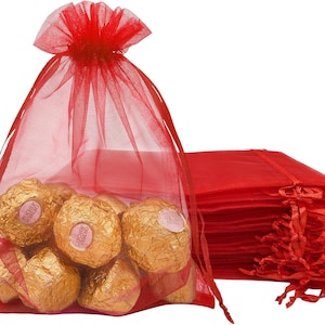 May include: Red organza gift bags with gold foil wrapped chocolates inside. The bags are made of sheer fabric and have a drawstring closure.