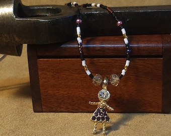 Item #12-36 -Beaded Necklace - Purple Dress Girl on a Purple, Gold, Black, White Strand