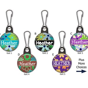 May include: Five zipper pulls with different floral designs and the name "Heather" in various fonts. The zipper pulls are available in a variety of colors, including blue, green, purple, and brown. Plus More Choices.