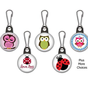 May include: Five zipper pulls with different designs. The designs include a pink owl, a green owl, a pink owl with a bow, a red ladybug with the words "love bug", and a black ladybug.