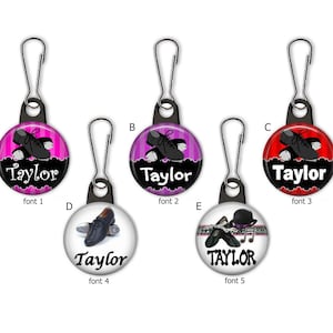 May include: A collection of five round zipper pulls with silver clasps. Each pull features a different design related to tap dancing, including tap shoes and a bowler hat. The name "Taylor" is printed on each pull in various fonts.
