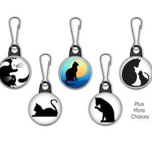 May include: Five zipper pulls with different black cat silhouettes on white round buttons. The designs include a cat with a kitten, a cat in a yin yang design, a cat sitting on a moon, a cat lying down, and a cat sitting up. The text "Plus More Choices" is visible below the zipper pulls.