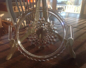 May include: A clear glass serving dish with a scalloped edge and a diamond pattern. The dish has two handles on the sides.