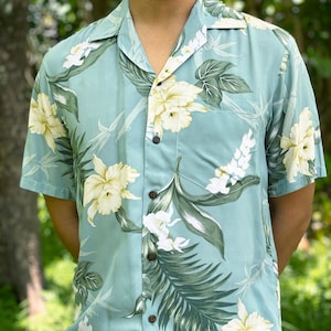May include: A light blue short-sleeved shirt with a floral print featuring white and yellow flowers and green leaves.